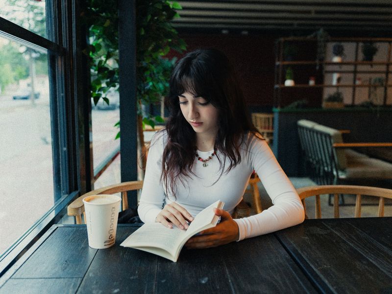 A person reading a book with a cup of coffee